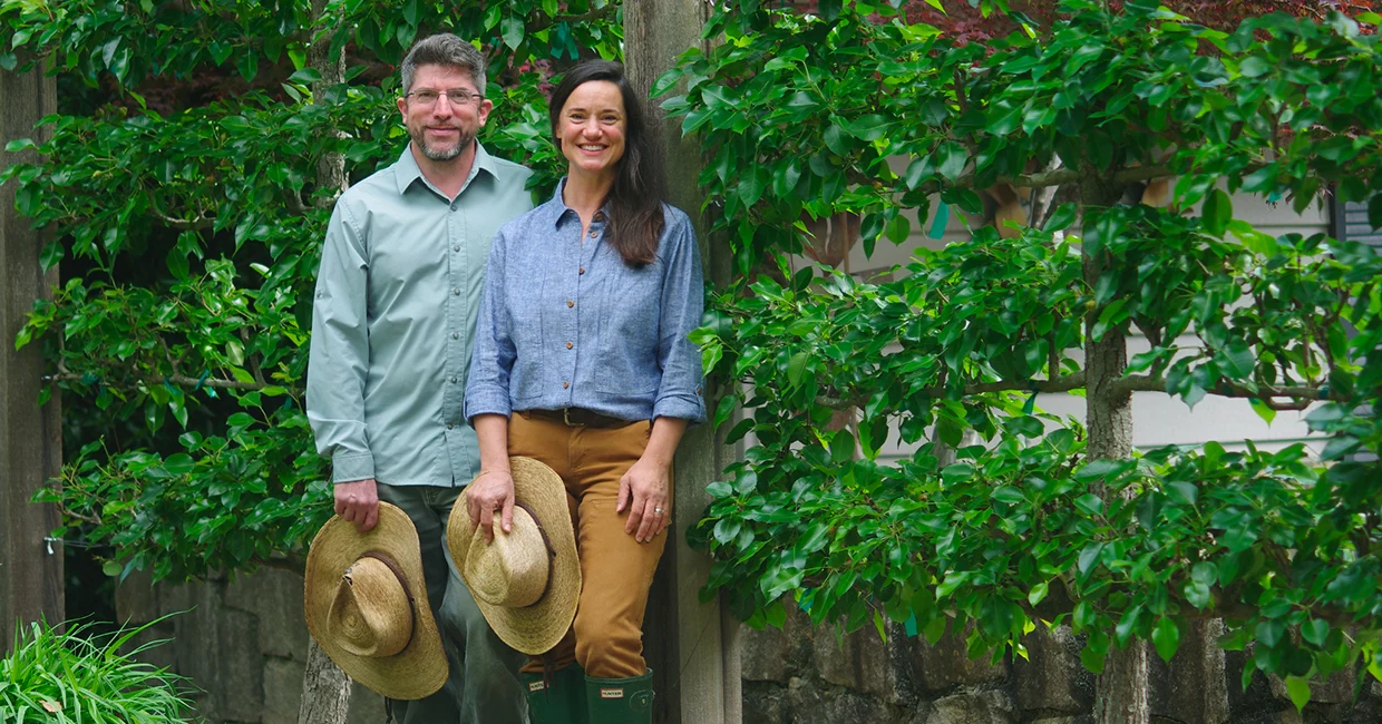 Matt and Krysta Johnson standing in front of lush greenery
